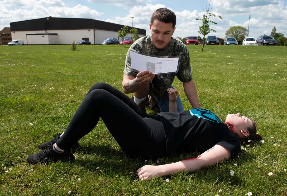 U.S. Air Force Senior Airman Tristian Riley, 423rd Medical Squadron laboratory technician, reads the instructions for assisting Airman Shalie Cino, a simulated casualty, in the first-ever joint mass-casualty medical training between the 423rd MDS and the 423rd Civil Engineer Squadron at RAF Alconbury, England, May 21, 2019. The training between medical specialists and firefighters enhanced their rapid response to mass-casualty situations. (U.S. Air Force photo by Airman 1st Class Jennifer Zima)