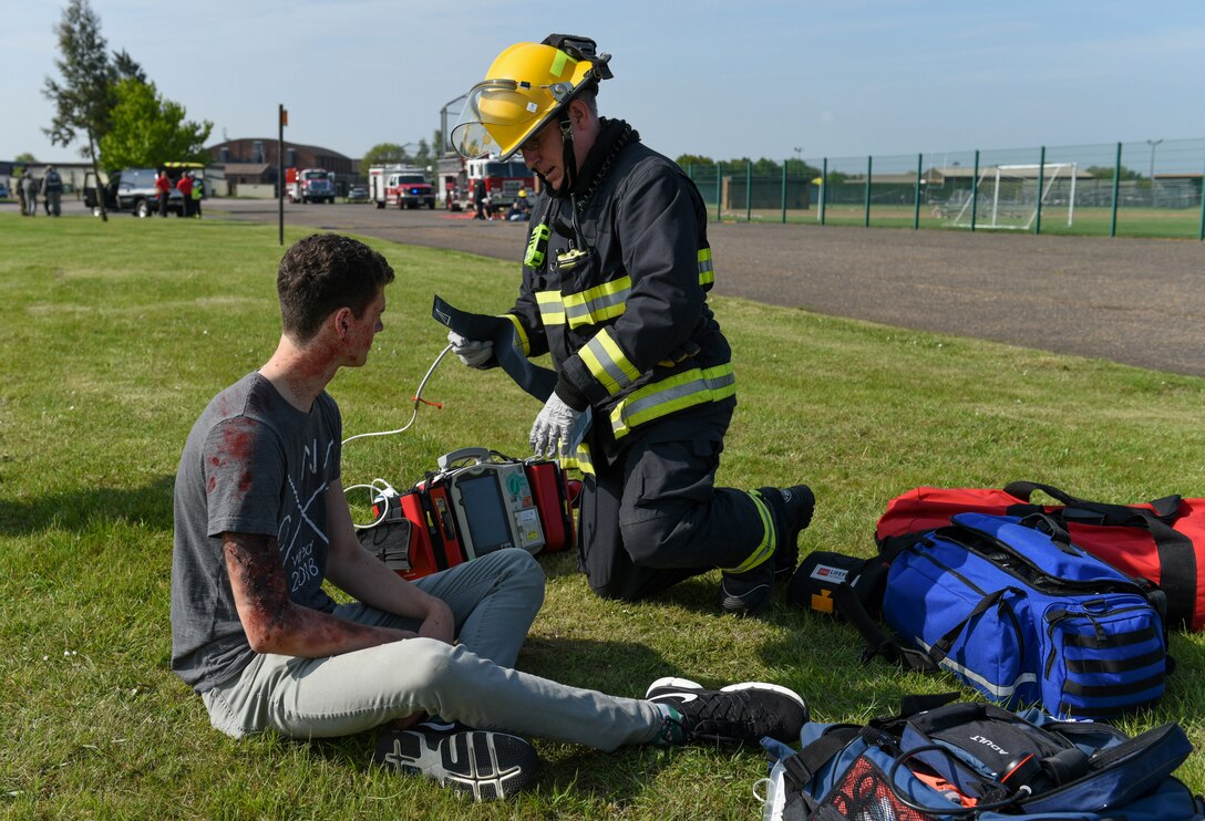 Andy Boon, 423rd Civil Engineer Squadron firefighter, prepares to measure the blood pressure of Garrett Evett, a simulated casualty, during a preparedness exercise at RAF Alconbury, England, May 20, 2019. The exercise tested the 501st Combat Support Wing preparedness and response capabilities to an emergency situation. (U.S. Air Force photo by Airman 1st Class Jennifer Zima)