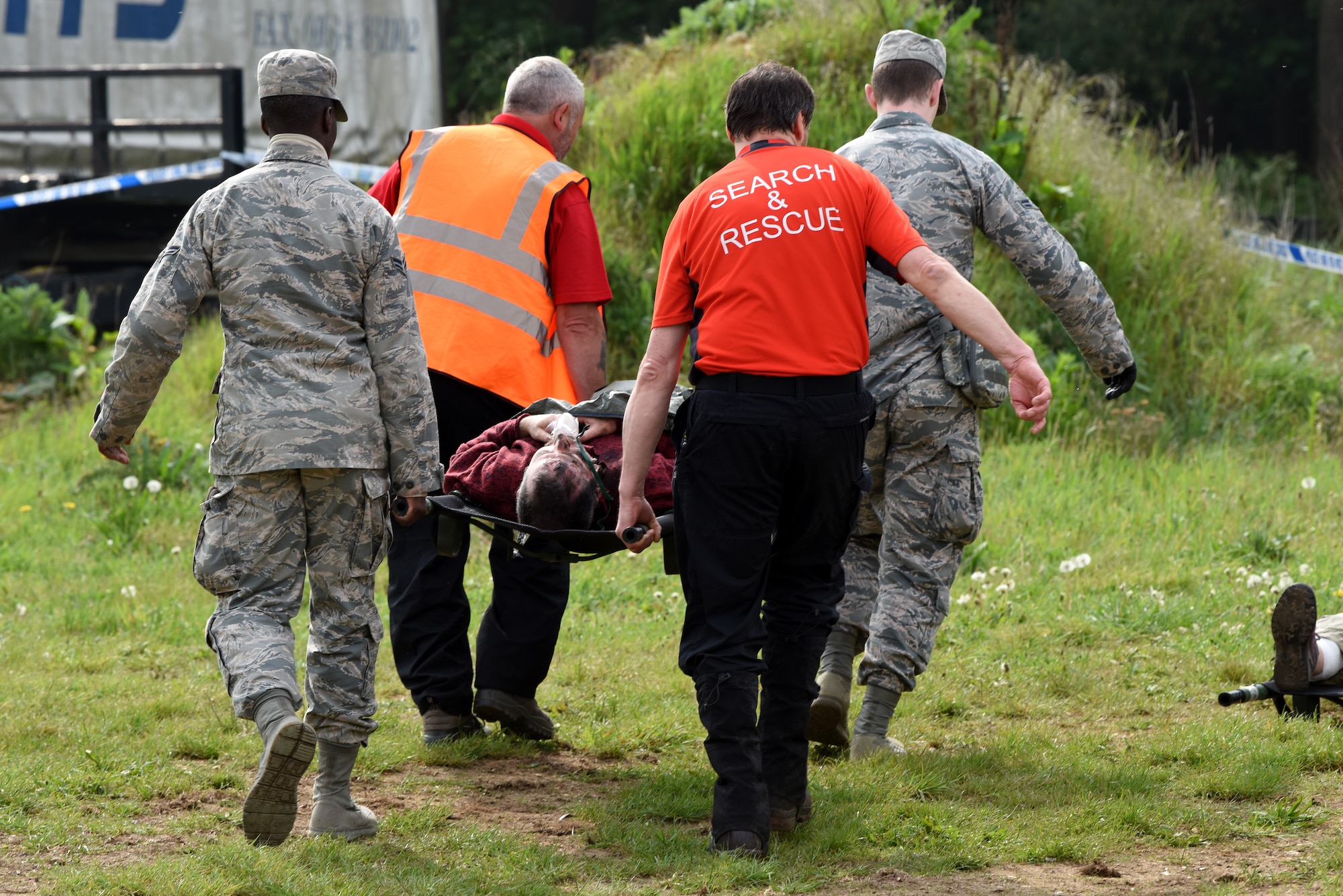 48th Medical Group Airmen and U.K. Suffolk Lowland Search and Rescue carry a simulated trauma patient to an ambulance at a British Army training site in Thetford, England, May 19, 2019. During the exercise, personnel from the 48th MDG trained with Suffolk Lowland Search and Rescue, Suffolk Police and Suffolk Accident Rescue Service, performing on-scene, life-saving care for 15 simulated trauma patients. (U.S. Air Force photo by Airman 1st Class Madeline Herzog