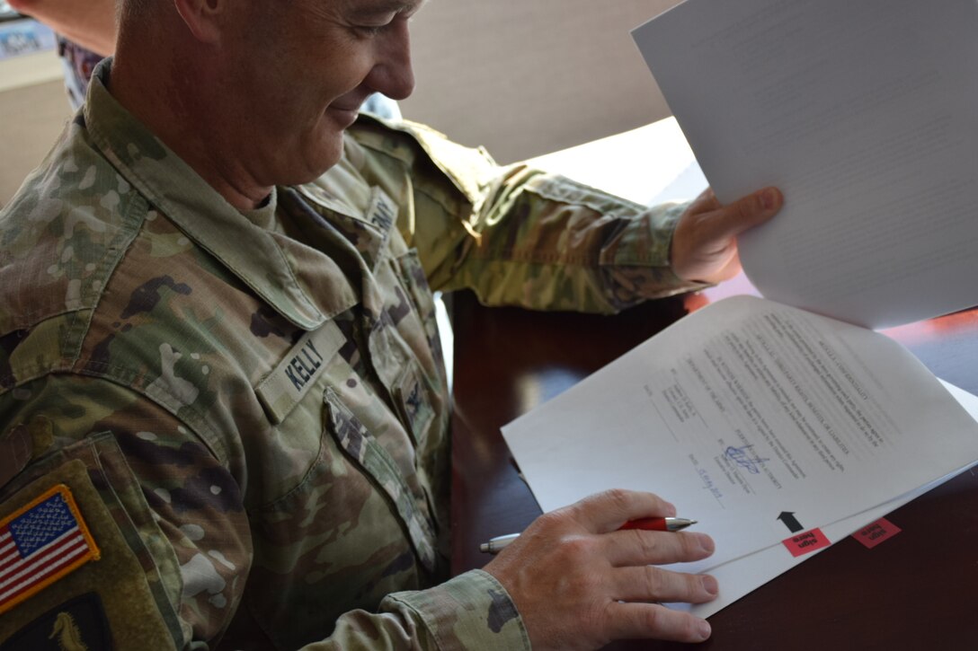 Col Kelly looks at the document prior to signing