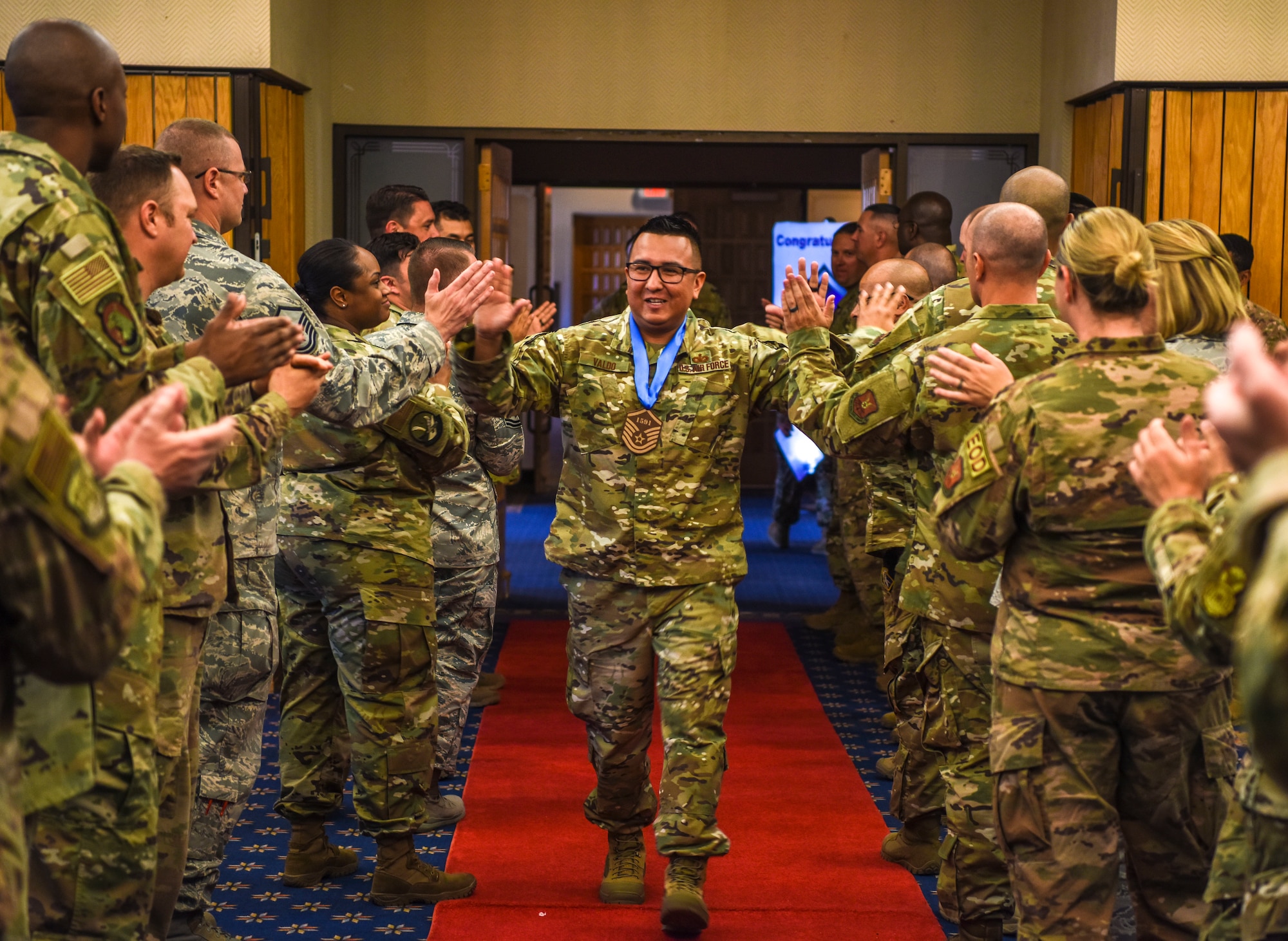 Master Sgt.-select Kendrick Valdo, 377th Air Base Wing Plans NCOIC, walks a gauntlet of high fives May 23, 2019, at the Mountain View Club here. Valdo was celebrating with dozens of selectees at the master sergeant release party. (U.S. Air Force photo by Senior Airman Eli Chevalier)