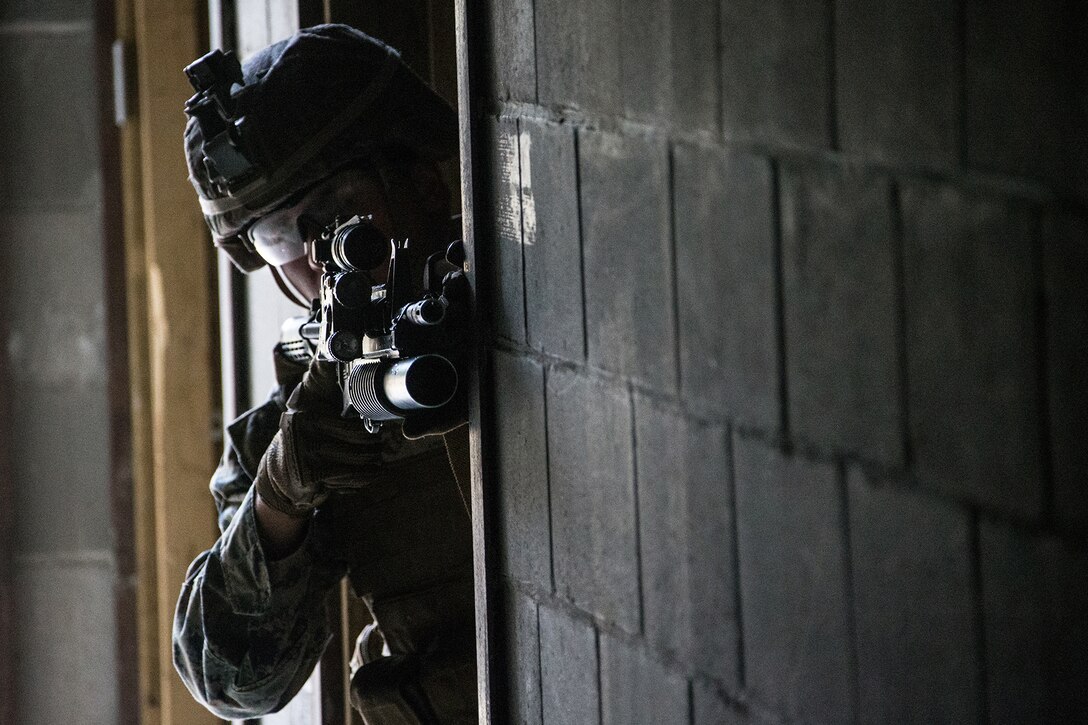 A Marine looks through a scope on a weapon.