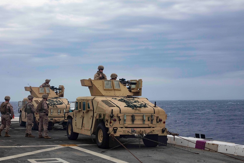 Marines in vehicle fire machine guns out to sea.