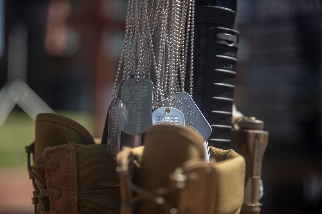 a batch of dog tags are displayed above military boots.