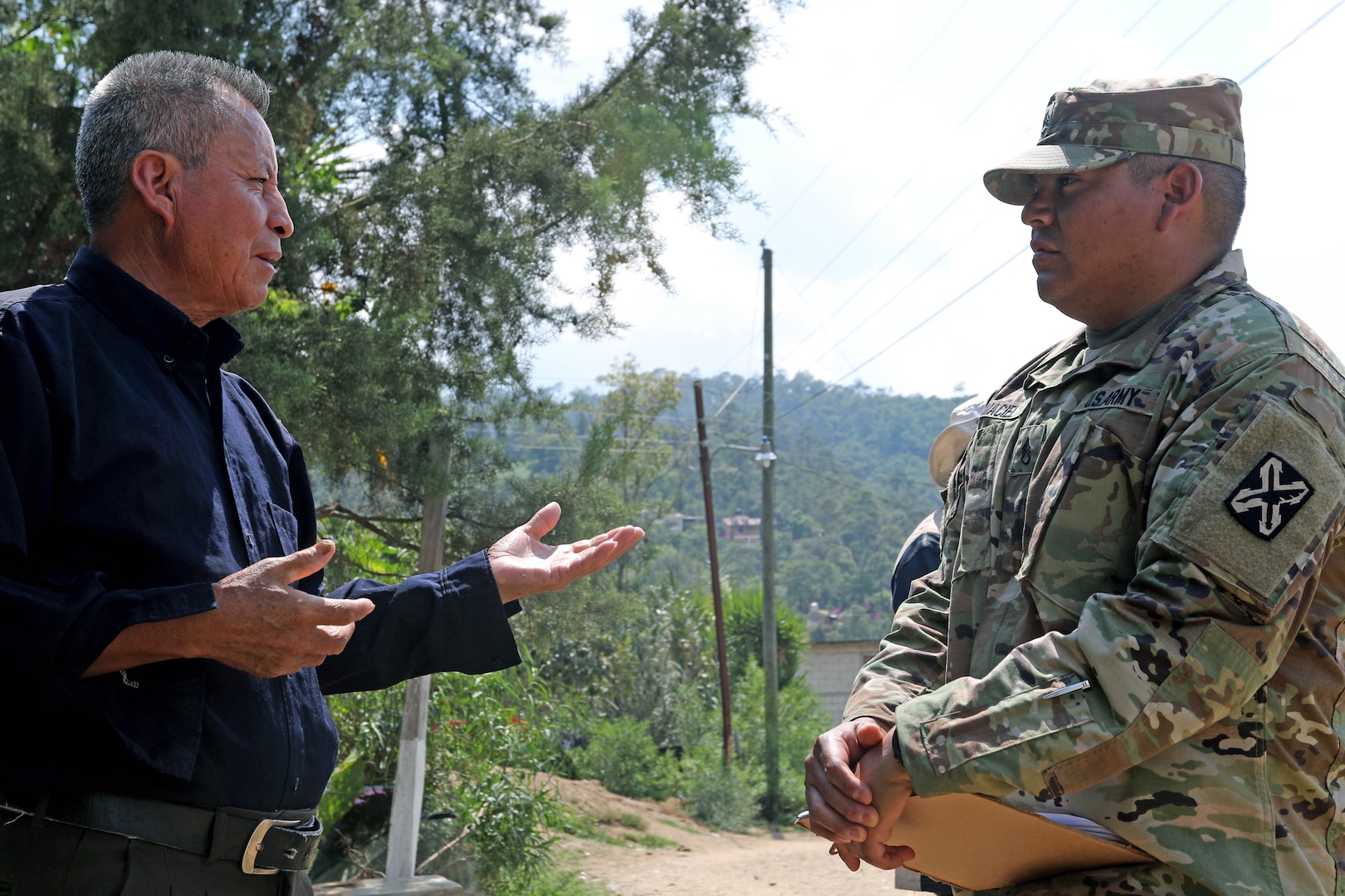 A man and a soldier converse outdoors.