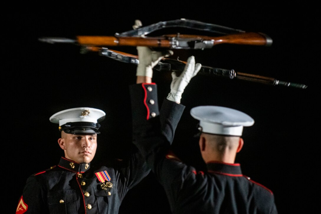 Marines spin guns above their heads during a performance.