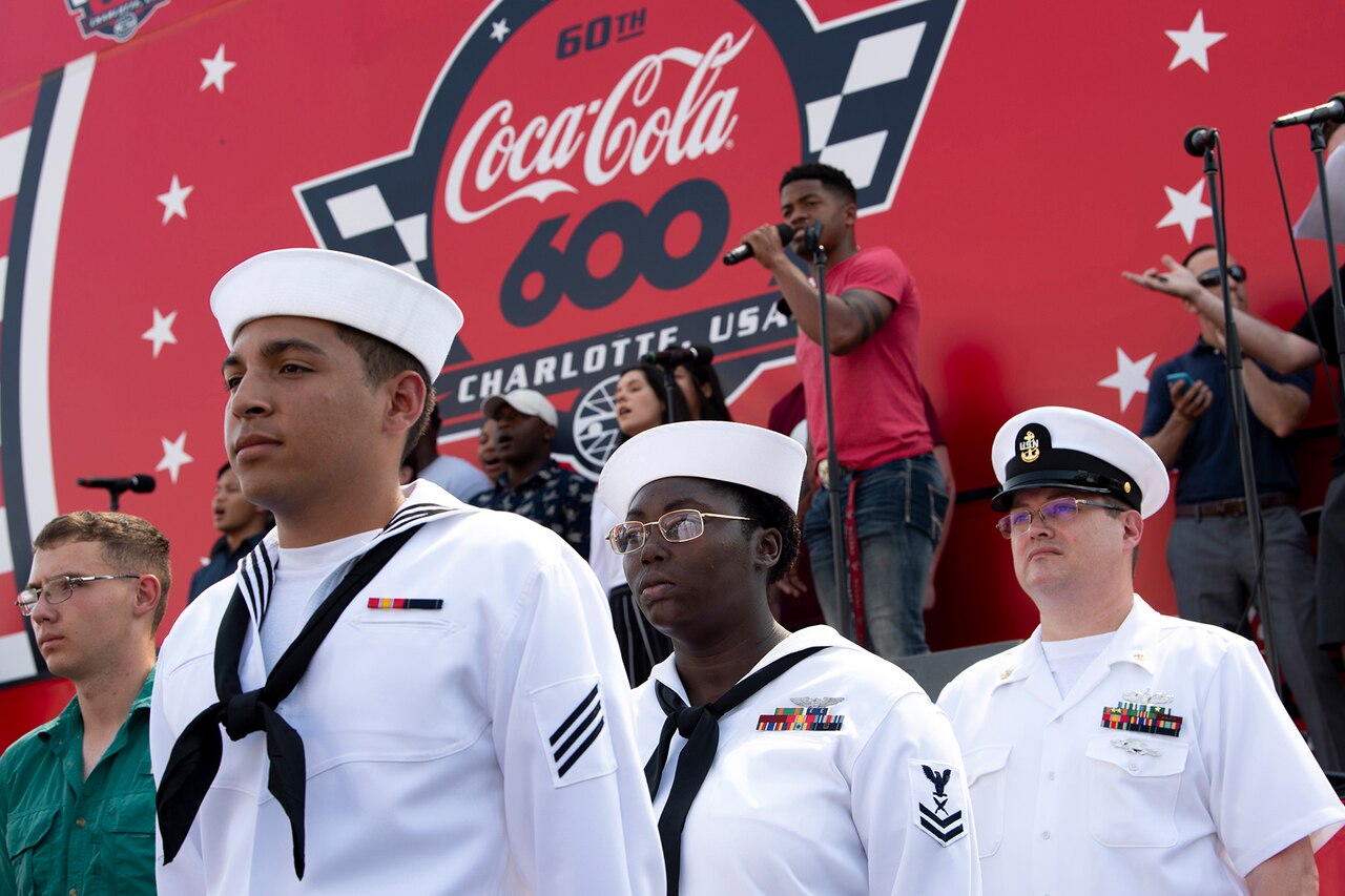 Sailors stand in front of a stage.