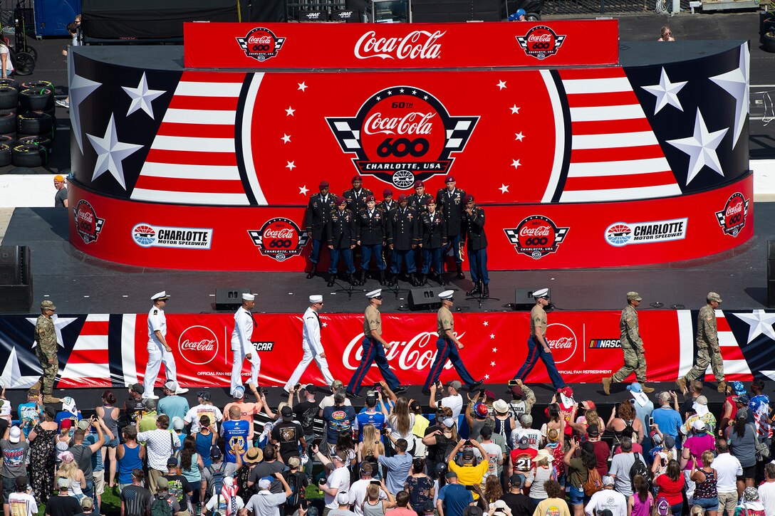 Service members walk across a stage.