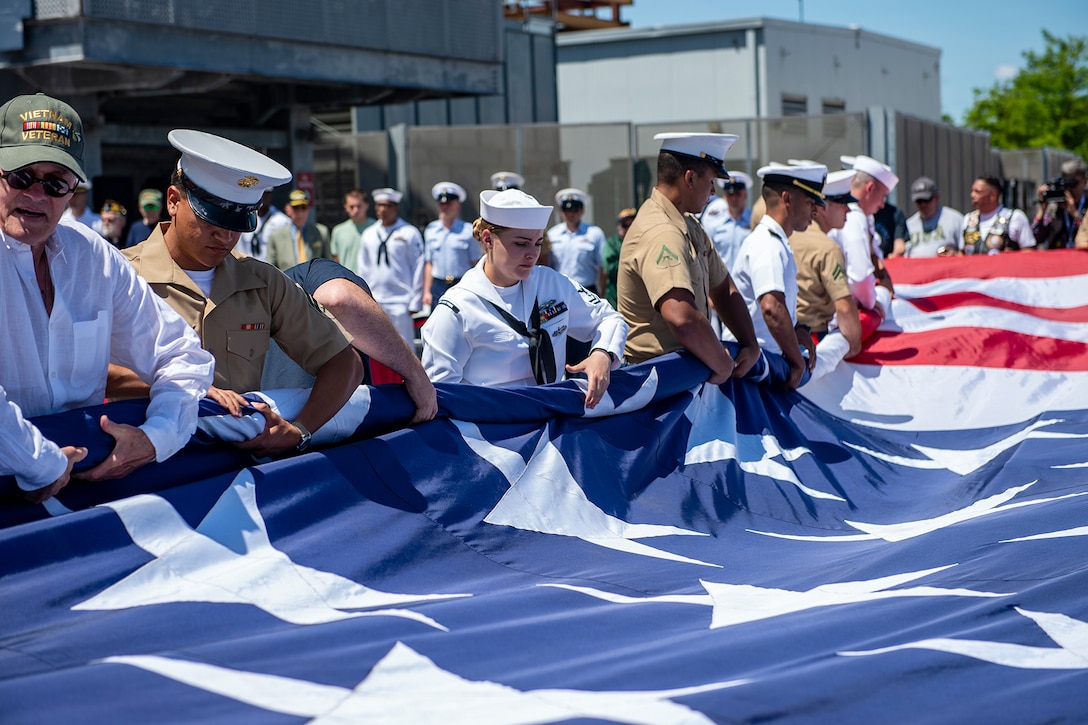 Service members and veterans roll the American flag together.