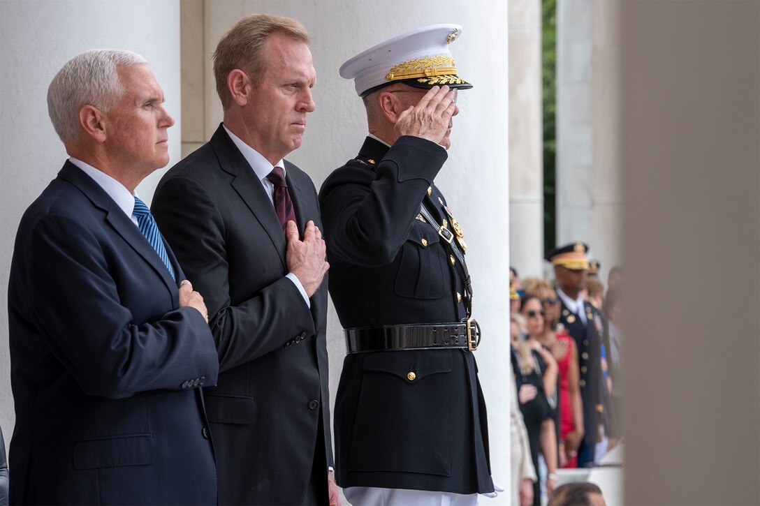Three men stand during a ceremony honoring fallen service members.