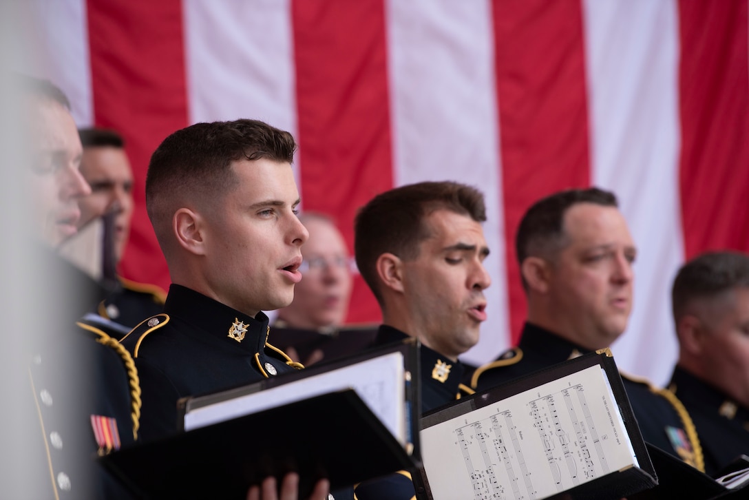 A group of men, holding music books, sing.