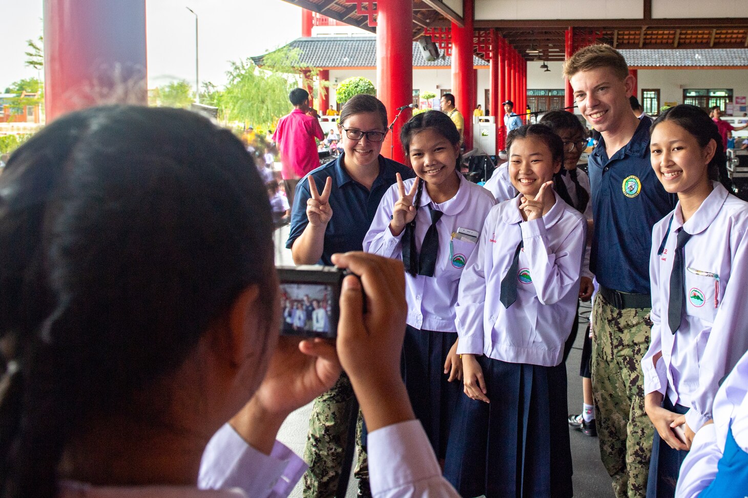 CHON BURI, Thailand (May 23, 2019) – U.S. Navy Musician 2nd Class Emileigh Kershaw and Musician 3rd Class Dakota Keller pose for a photo with Wutthi Wittaya school students following a host nation outreach engagement as part of Pacific Partnership 2019. Pacific Partnership, now in its 14th iteration, is the largest annual multinational humanitarian assistance and disaster relief preparedness mission conducted in the Indo-Pacific. Each year the mission team works collectively with host and partner nations to enhance regional interoperability and disaster response capabilities, increase security and stability in the region, and foster new and enduring friendships in the Indo-Pacific.