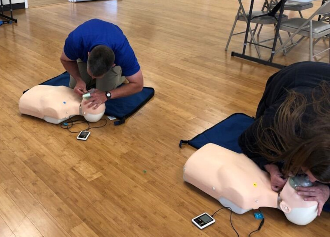Man and woman practice CPR on training body.