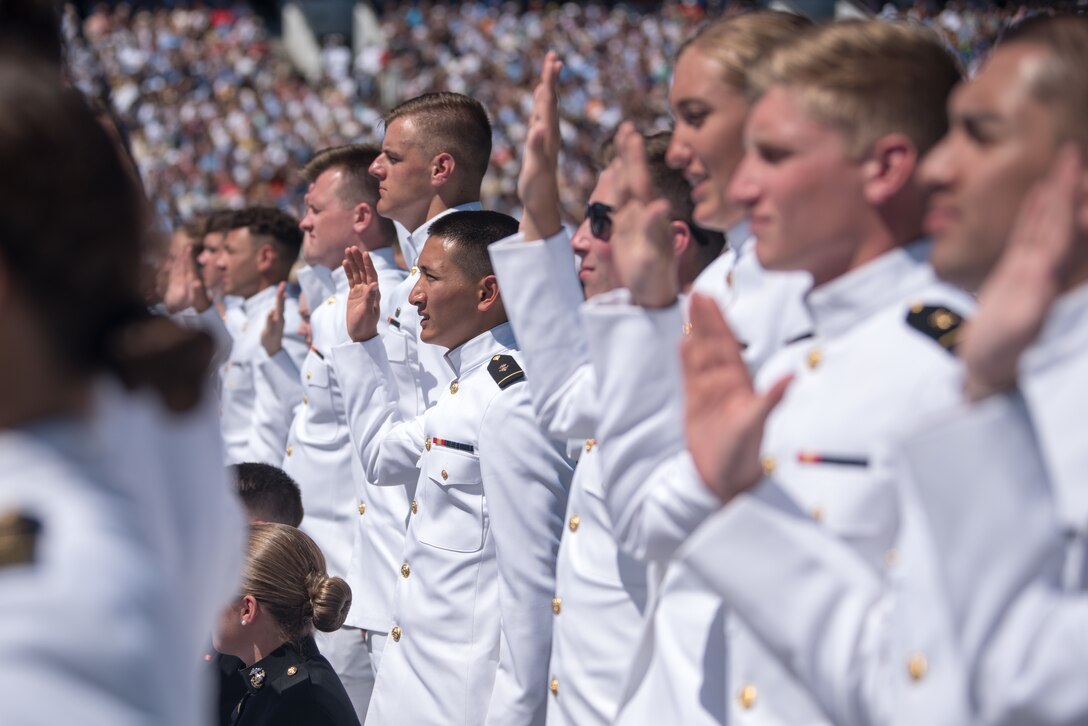 Uniformed men and women raise their right hands.