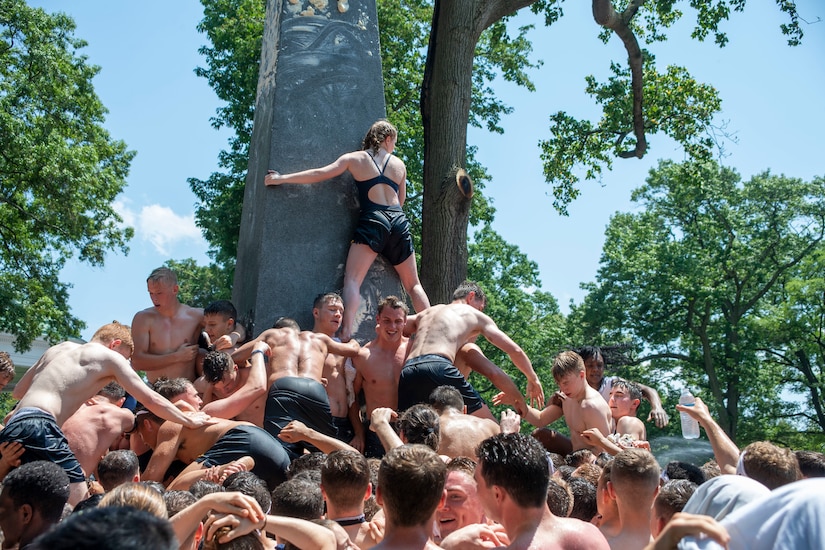 Midshipmen climb greased obelisk.