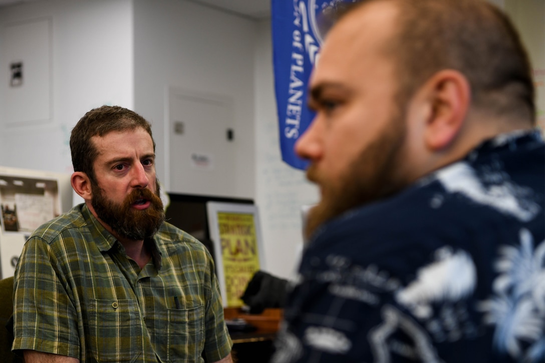 Two men sitting down talking to each other.