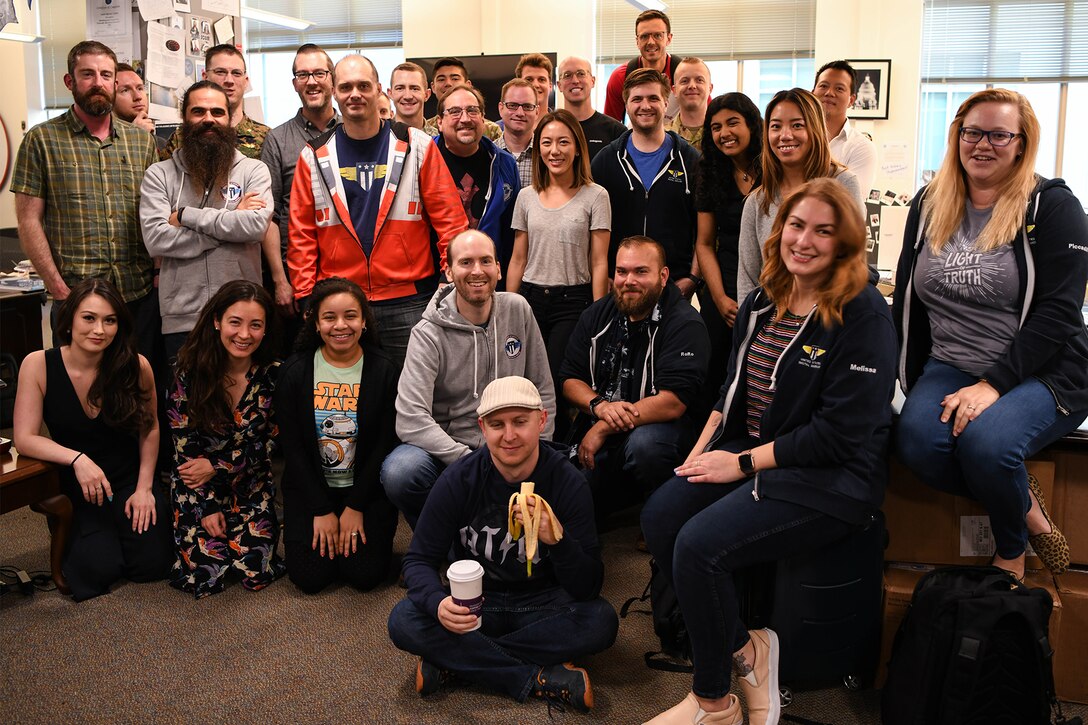 A group of people posing for a group photo inside an office.