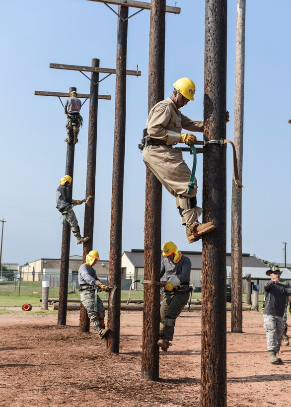 366th Training Squadron electrical systems apprentice course students climb up poles during training at Sheppard Air Force Base, Texas, May 28, 2019. Using a collection of straps, metal ridges and the super squeeze belt, the climbers are able to grip the pole and eliminates the danger and fear of slipping. (U.S. Air Force photo by Senior Airman Ilyana A. Escalona)