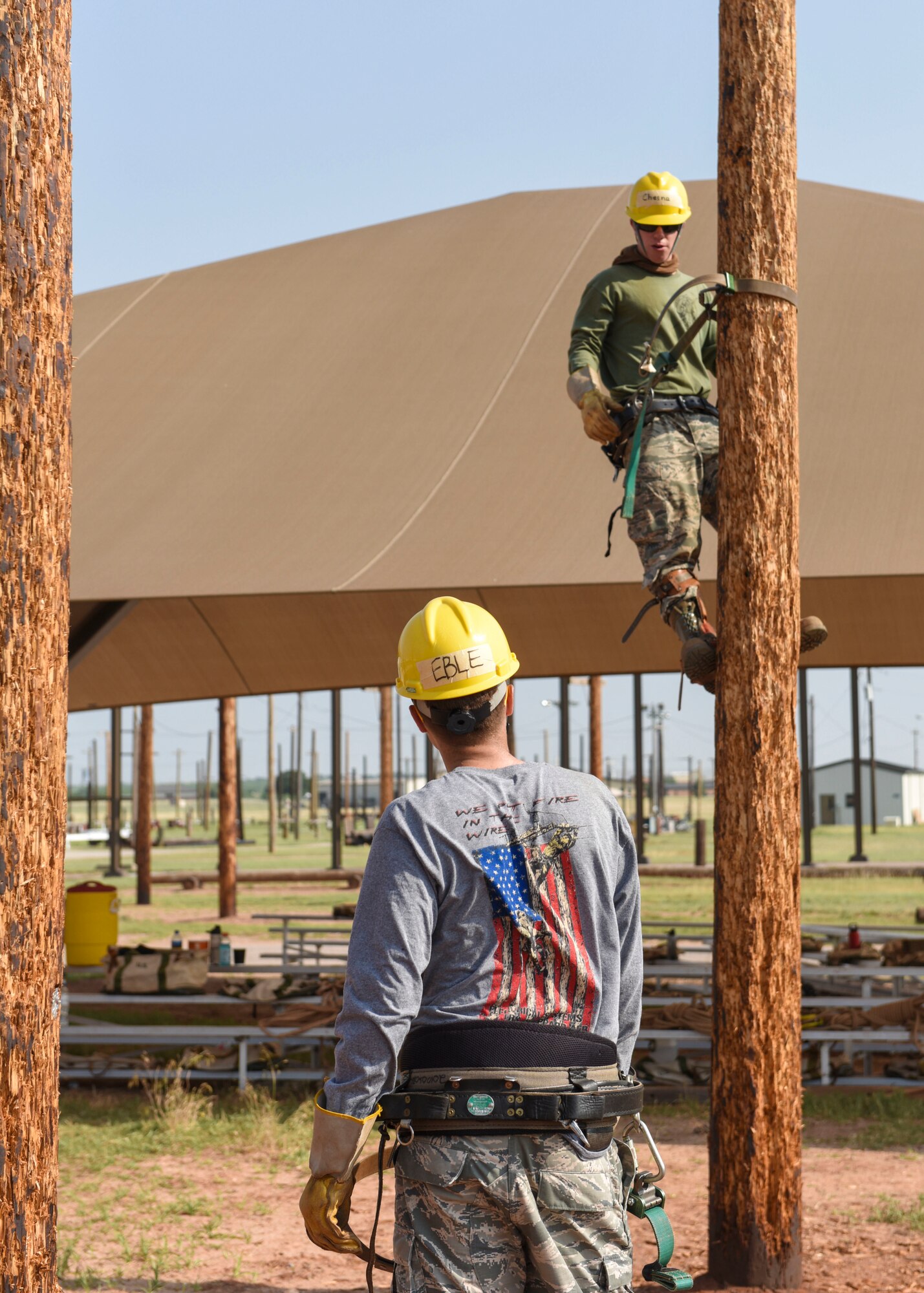 366th Training Squadron electrical systems apprentice course students climb up poles during training at Sheppard Air Force Base, Texas, May 28, 2019. Using a collection of straps, metal ridges and the super squeeze belt, the climbers are able to grip the pole and eliminates the danger and fear of slipping. (U.S. Air Force photo by Senior Airman Ilyana A. Escalona)