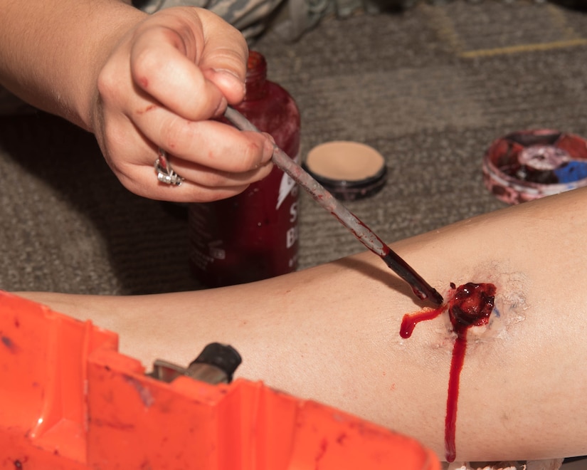 U.S. Air Force Staff Sgt. Kailtlin Eller, 633d Medical Group Basic Life Support program director for Joint Base Langley-Eustis, applies a simulated gunshot wound to a volunteer on JBLE, Virginia, May 17, 2019. The volunteers were asked to simulate a range of medical injuries from gunshot wounds to allergic reactions. (U.S. Air Force photo by Airman 1st Class Marcus M. Bullock)