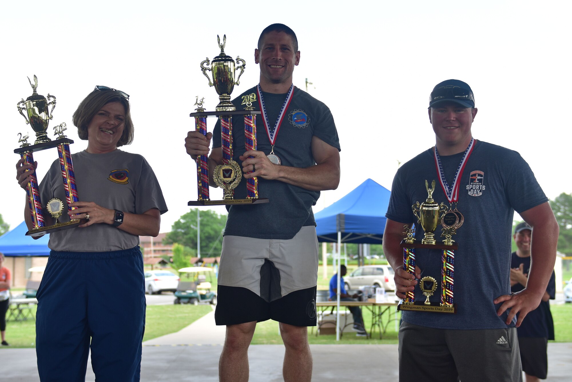 Airmen hold up a first, second, and third place trophy up.