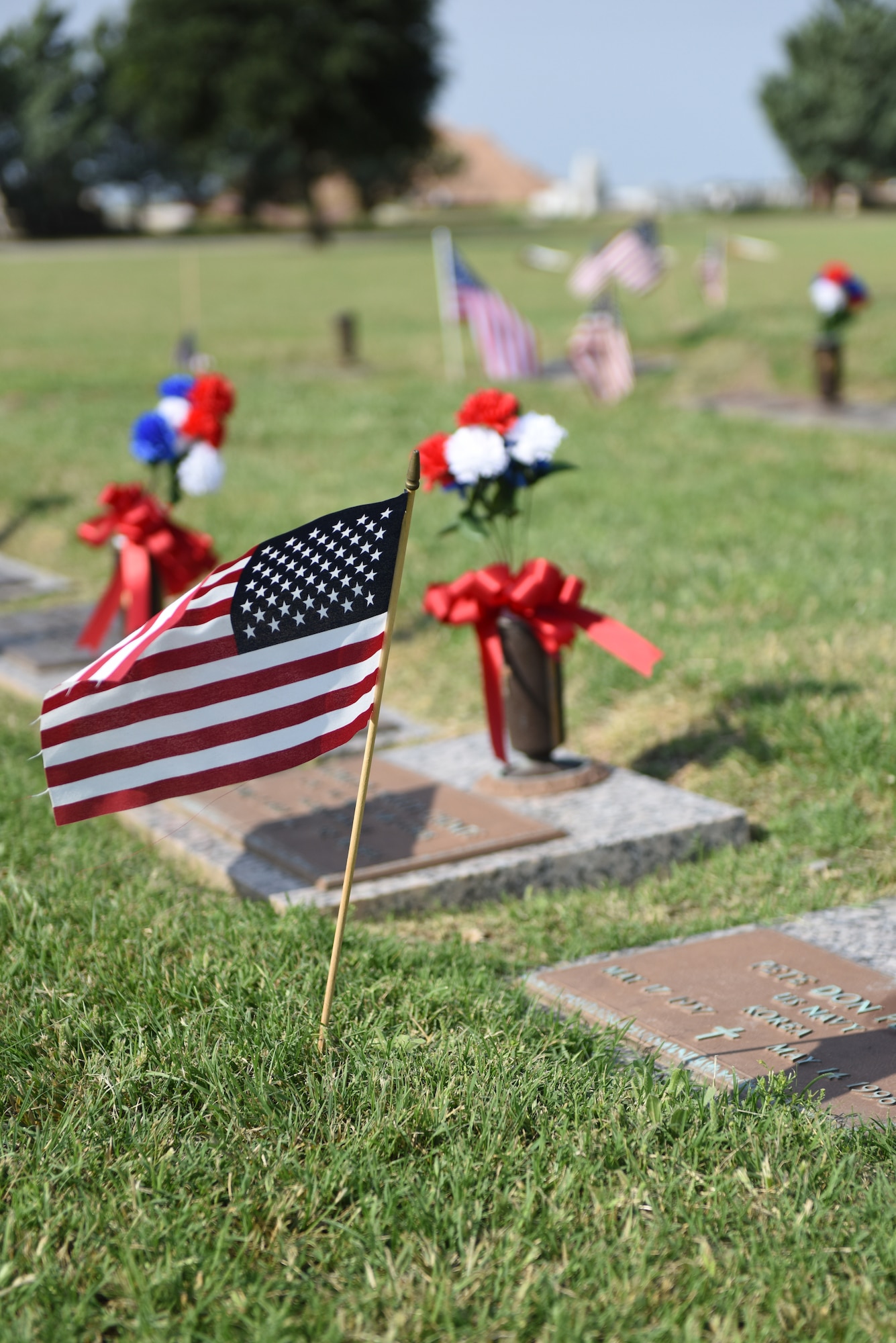 U.S. flags decorate the tombstones of service members during the eighth annual Lawnhaven Memorial Gardens Memorial Day Ceremony in San Angelo, Texas, May 27, 2019. The ceremony was held to honor the service and sacrifice of fallen armed forces members. (U.S. Air Force photo by Senior Airman Seraiah Hines/Released)