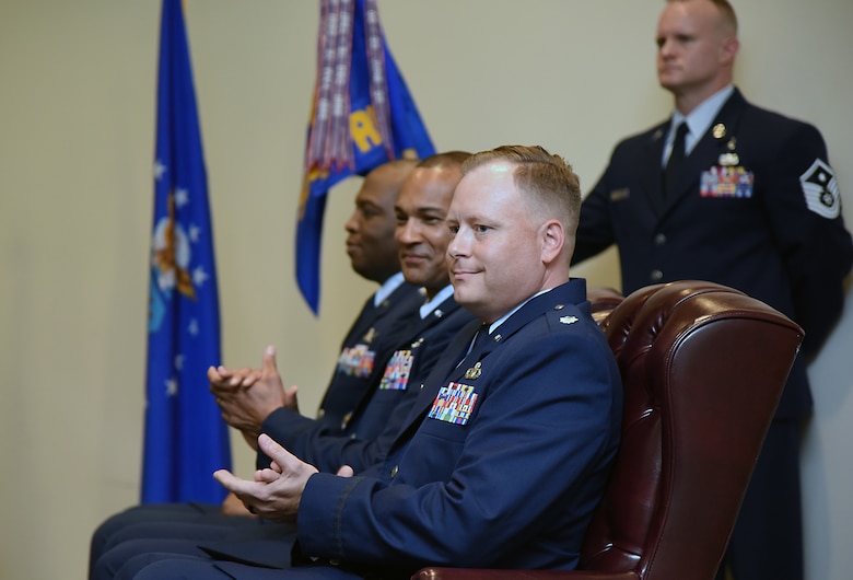 U.S. Air Force Col. Leo Lawson, Jr., 81st Training Group commander, Lt. Col. Billy Wilson, Jr., outgoing 334th Training Squadron commander, and Lt. Col. Harry James, incoming 334th TRS commander, sit on stage during the 334th TRS change of command ceremony in the Roberts Consolidated Aircraft Maintenance Facility at Keesler Air Force Base, Mississippi, May 23, 2019. James assumed command from Wilson with the passing of the guidon. The passing of the guidon is a ceremonial symbol of exchanging command from one commander to another.. (U.S. Air Force photo by Kemberly Groue)