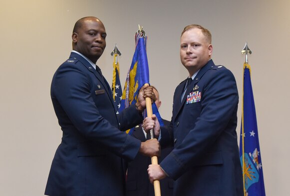 U.S. Air Force Col. Leo Lawson, Jr., 81st Training Group commander, passes the 334th Training Squadron guidon to Lt. Col. Harry James, 334th TRS commander, during the 334th TRS change of command ceremony in the Roberts Consolidated Aircraft Maintenance Facility at Keesler Air Force Base, Mississippi, May 23, 2019. The passing of the guidon is a ceremonial symbol of exchanging command from one commander to another. (U.S. Air Force photo by Kemberly Groue)