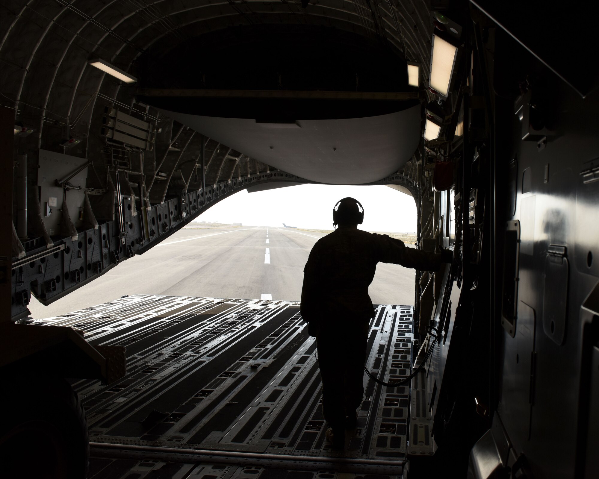 U.S. Air Force Staff Sgt. James Armstrong, 21st Airlift Squadron loadmaster, looks out the back of a C-17 Globemaster III May 19, 2019, at an undisclosed location. The C-17 is capable of rapid strategic delivery of troops and cargo anywhere in the world. (U.S. Air Force photo by 2nd Lt. R. Michael Longoria)