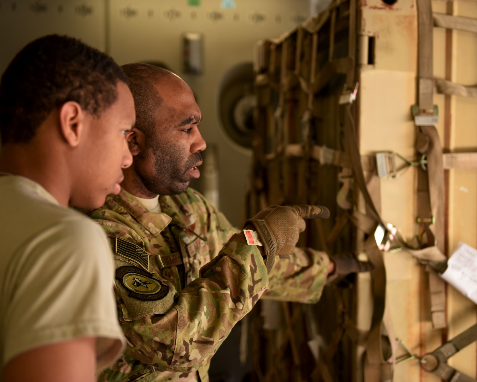 U.S. Air Force Staff Sgt. James Armstrong, right, and Airman 1st Class Alan Collier, 21st Airlift Squadron loadmasters, discuss how to offload U.S. Army equipment from a C-17 Globemaster III May 24, 2019, at an undisclosed location. The loadmasters are responsible for ensuring all cargo and passengers on the C-17 are ready for tactical and strategic airlift mission around the world. (U.S. Air Force photo by 2nd Lt. R. Michael Longoria)