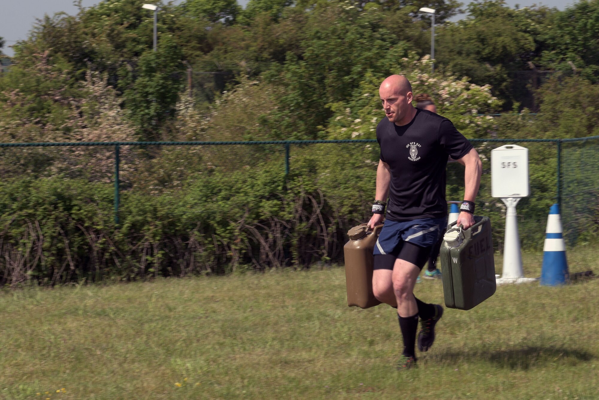 U.S. Air Force Tech. Sgt. Nicolas Henson, 100th Security Forces Squadron NCO-in-charge of physical security, performs the jerry can relay during the Highland Games at RAF Mildenhall, England, May 23, 2019. The Jerry cans were filled with water for the contest. (U.S. Air Force photo by Senior Airman Benjamin Cooper)