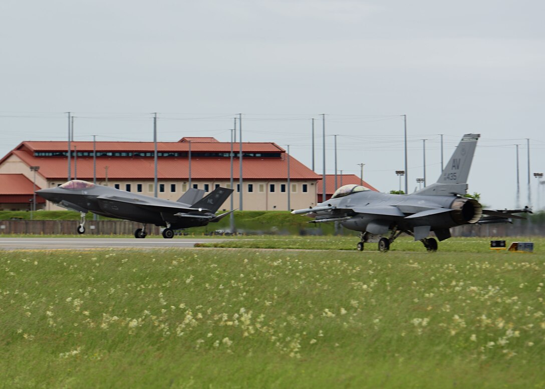 An F-35A Lightning II lands while an F-16 Fighting Falcon waits to take off at Aviano Air Base, Italy, May 29, 2019.