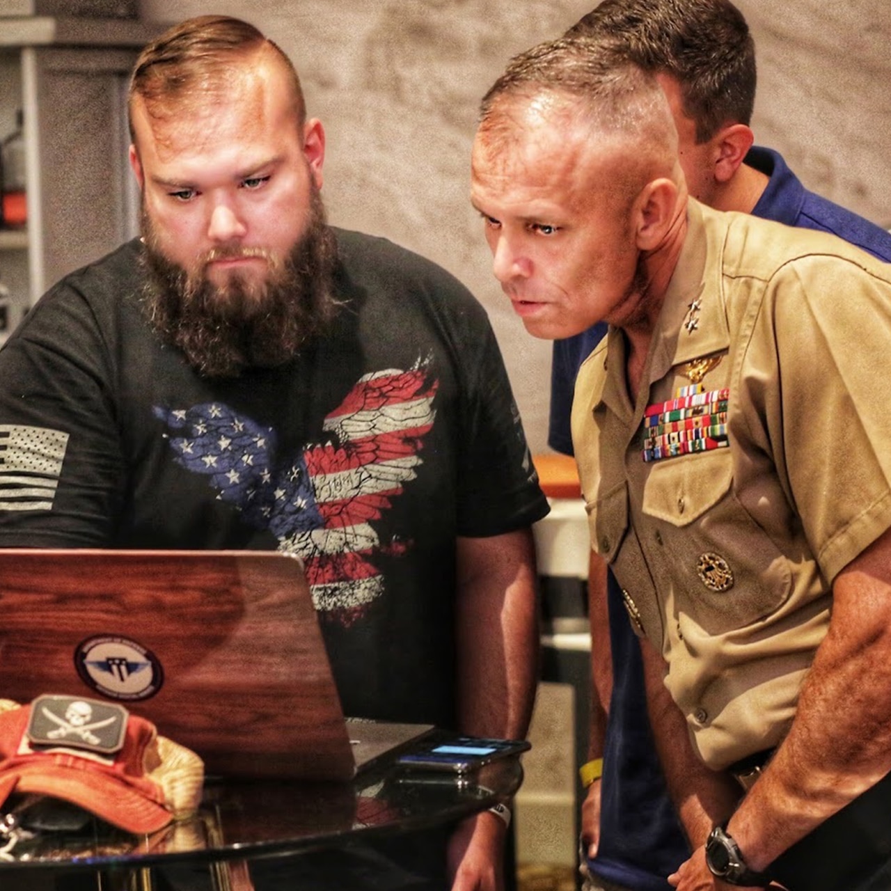 Civilian and Marine Corps general look at laptop screen.