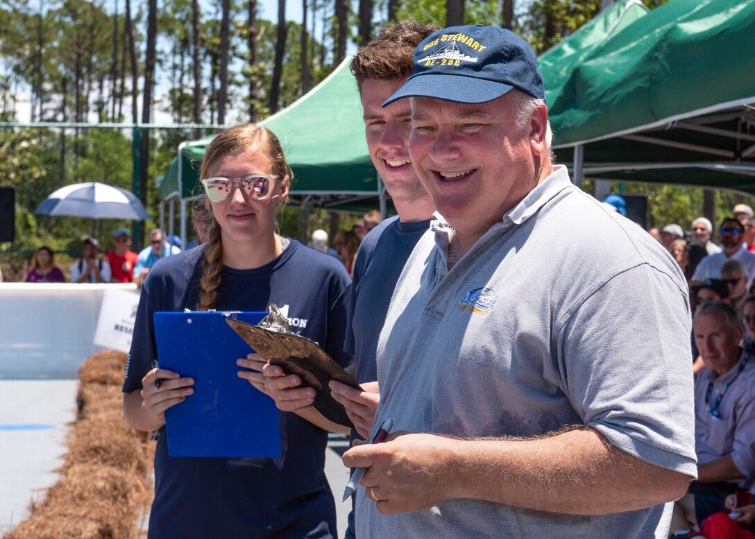 Ed Stewart, Naval Surface Warfare Center Panama City Division technical director, and Naval Research Enterprise Intenship Program interns observe the action at the 2019 Director's Cup competition at the Naval Support Activity Panama City Roller Hockey Rink May 22.