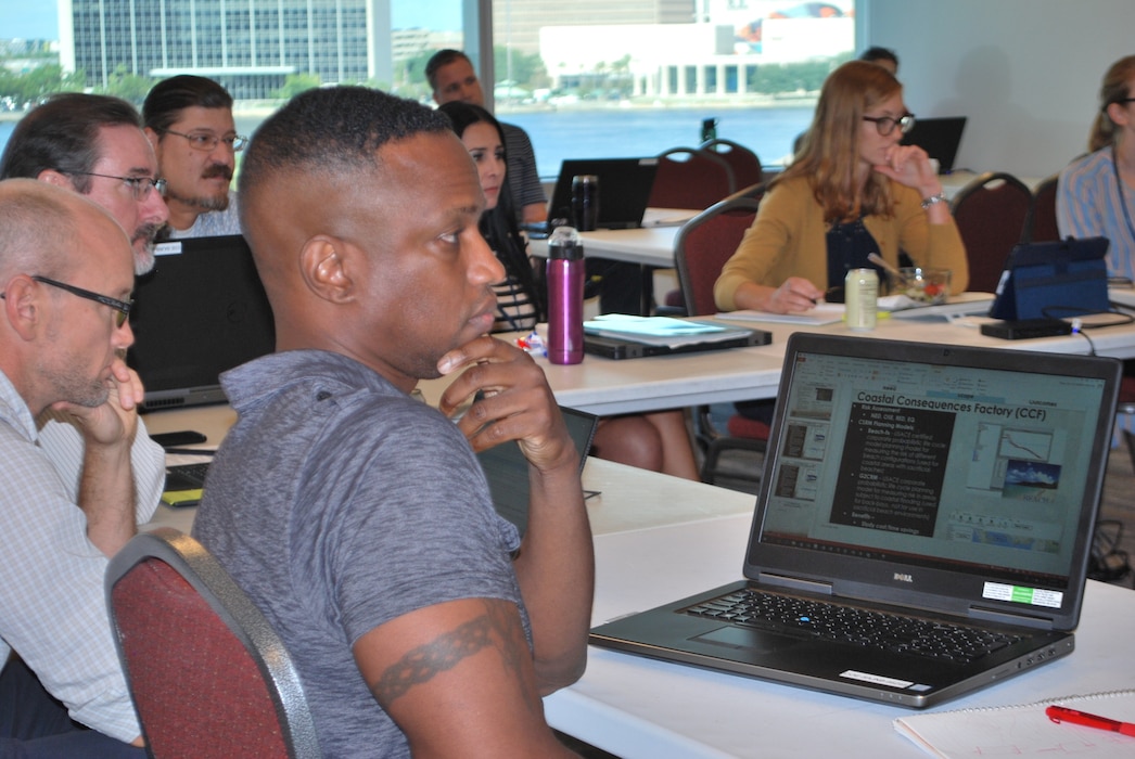 people sitting around a conference table, a laptop on the right