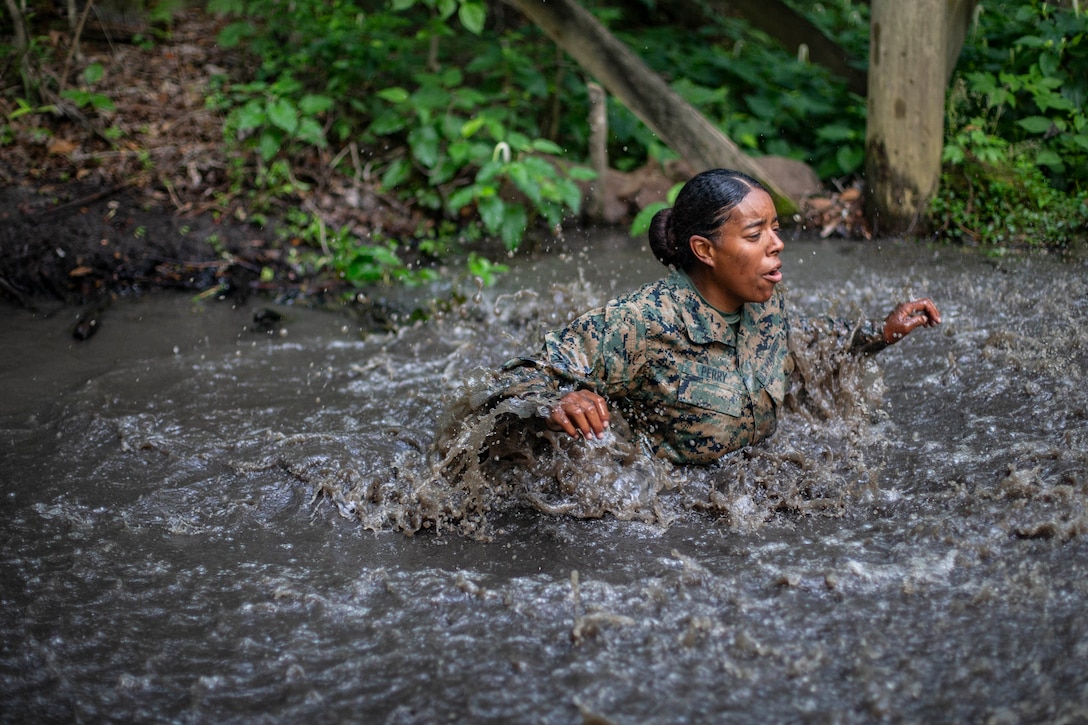 A Marine wades through muddy, chest-deep water.