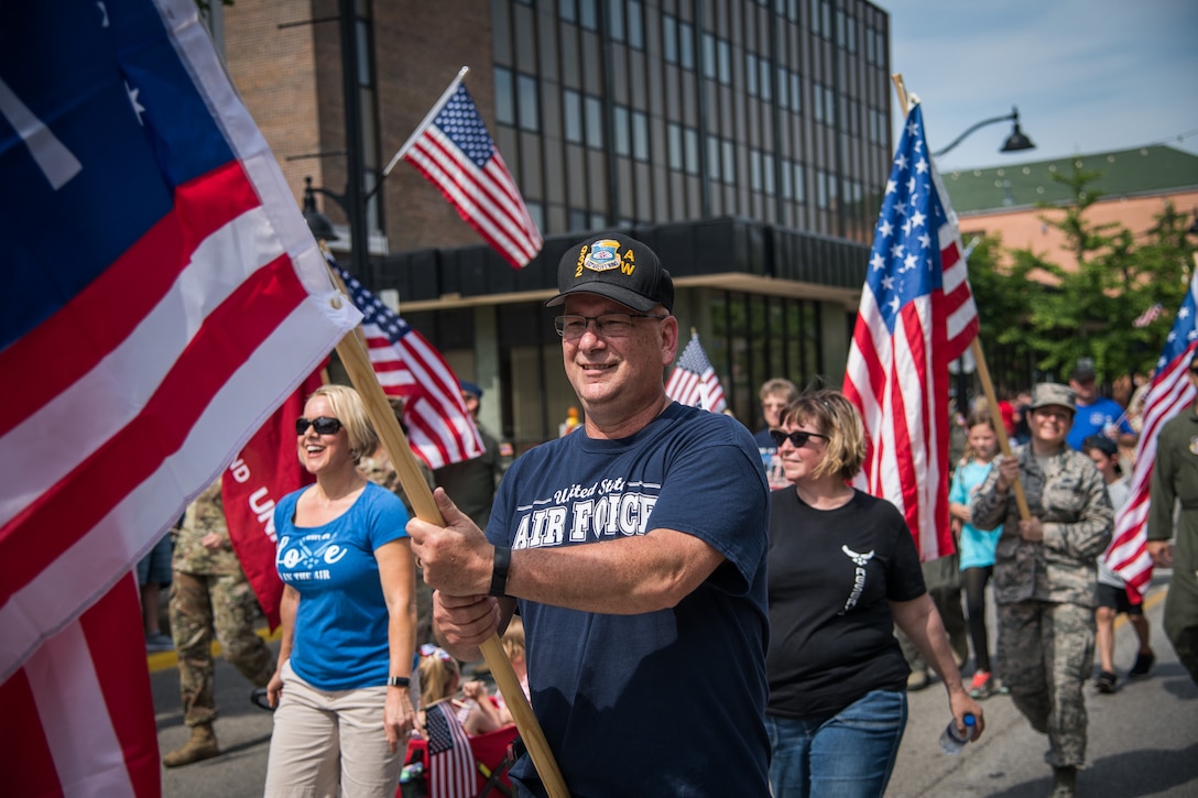 Master Sgt. Gerald Sonnenberg (retired) former historian for the 932nd Airlift Wing, carries one of the flags he purchased and mounted on homemade poles used during the Belleville Memorial Day Parade, May 27, 2019, Belleville, Illinois.  Using his love of history, Sonnenberg put constructed poles with flags representing various symbolic flags of the United States of America and Armed Forces. (U.S. Air Force photo by Christopher Parr)