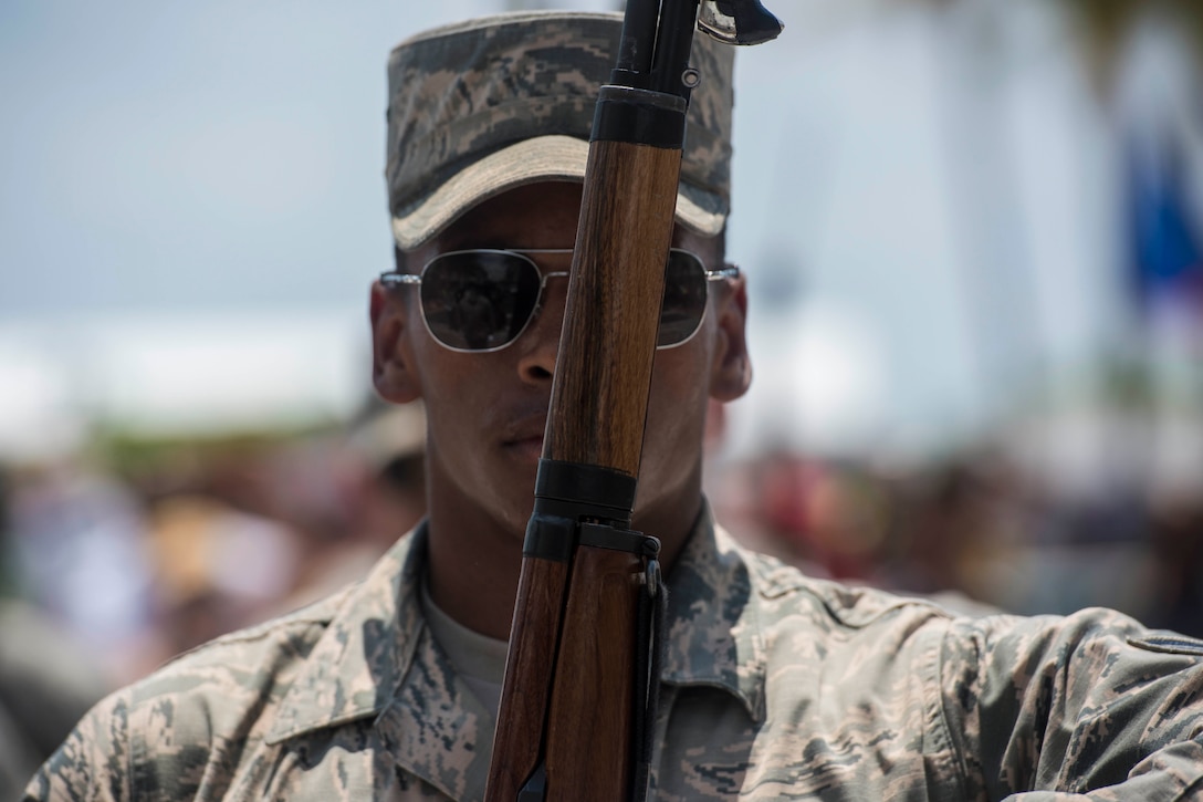 An airman holds a weapon across his face.