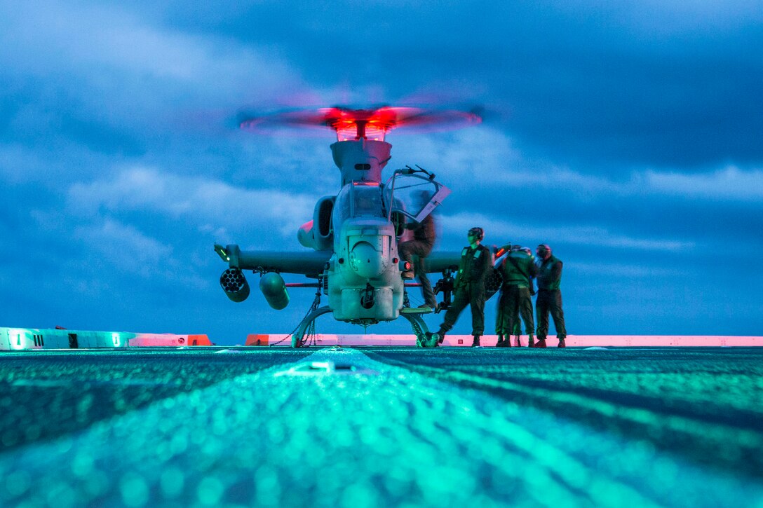 Marines stand next to a helicopter.