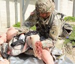 Sgt. Moises Ortiz, Training Support Activity, Headquarter Support Company, Health Readiness Center of Excellence, applies a tourniquet on a simulated leg amputation while competing in the Tactical Combat Casualty Care lane.