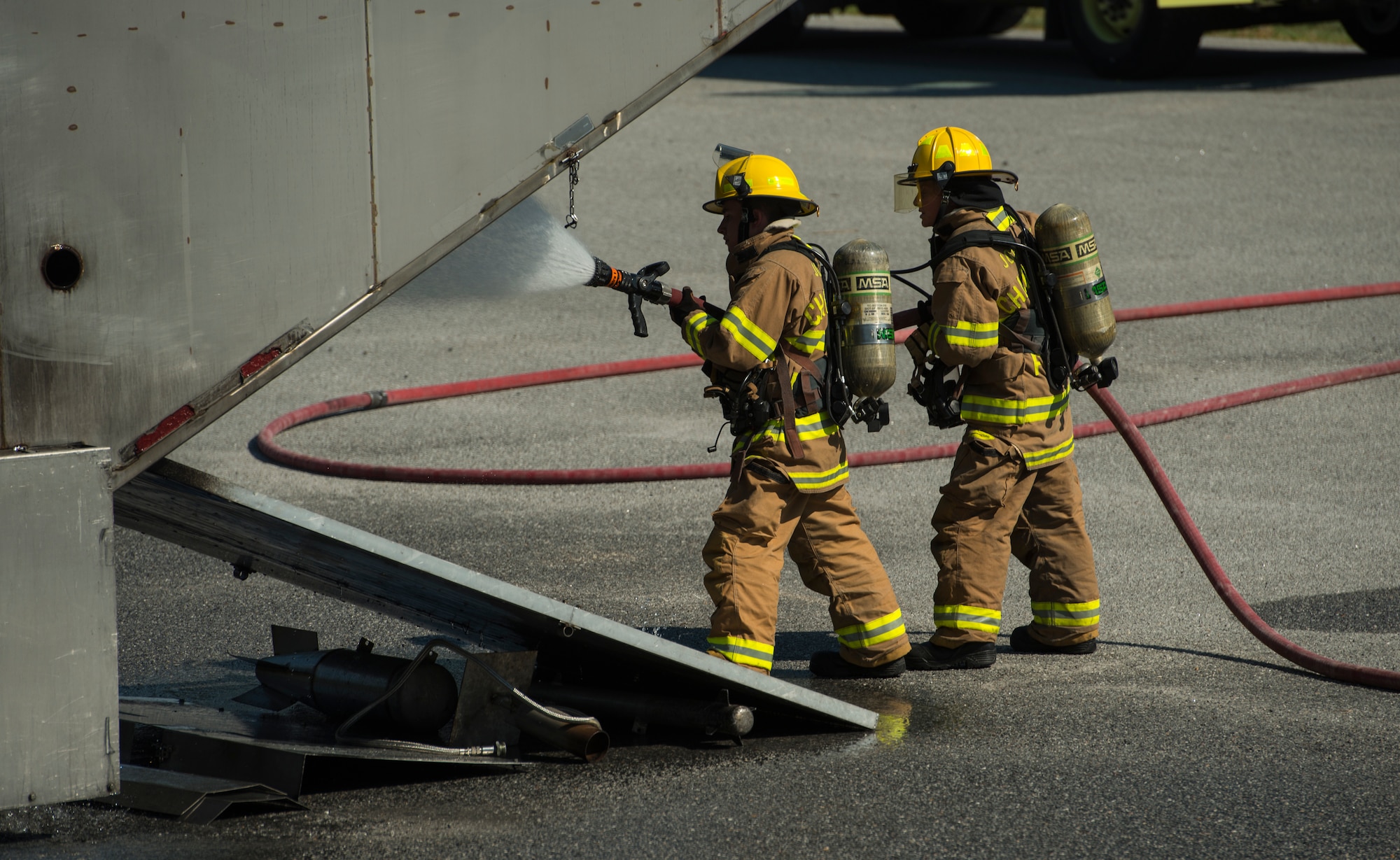 Airman 1st Class Cameron Edwards, left, a firefighter assigned to the 628th Civil Engineer Squadron and Airman 1st Class Shae Sibert, a firefighter assigned to the 628th CES, spray water onto a mobile aircraft fire training unit May 27, 2019, at Joint Base Charleston, S.C.