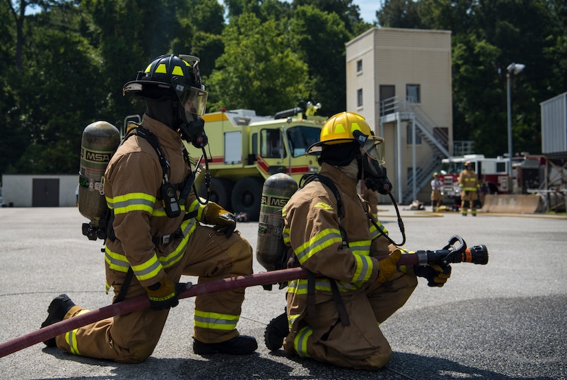 Airman 1st Class Cameron Edwards, right, a firefighter assigned to the 628th Civil Engineer Squadron and Airman 1st Class Patrick Cummings, a firefighter assigned to the 628th CES, spray water onto a mobile aircraft fire training unit May 27, 2019, at Joint Base Charleston, S.C.