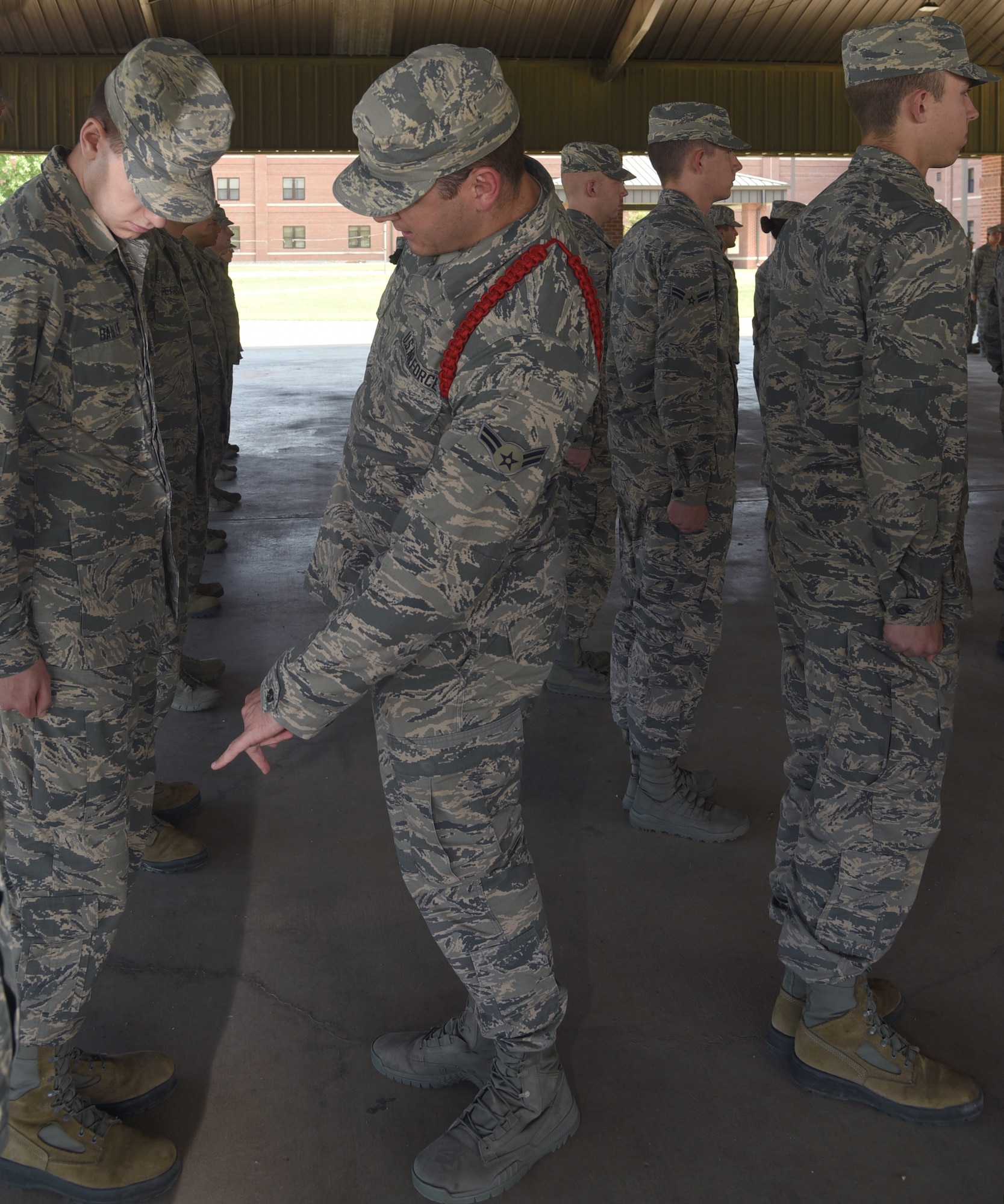 U.S. Air Force Airman 1st Class Jordan Stidham, 316th Training Squadron student and a red rope level Airman Leader, indicates an unclipped string on a fellow Airman’s uniform during an open rank inspection outside the 316th TRS  on Goodfellow Air Force Base, Texas, May 14, 2019. Stidham’s red rope distinguishes him as an Airman Leader who holds the highest level responsibility. (U.S. Air Force photo by Airman 1st Class Abbey Rieves/Released)