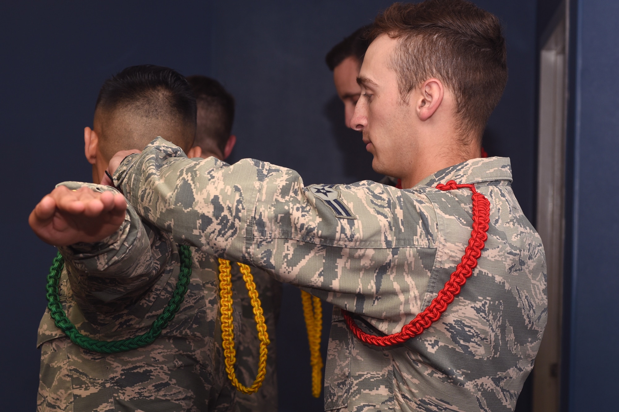 U.S. Air Force Airman 1st Class Joshua Winston, 316th Training Squadron student and a red rope level Airman Leader, removes the green rope from Airman 1st Class Vinz Dy Cruz, 316th TRS student, in order to promote Dy Cruz to a yellow rope during an Airman Leader meeting at the 316th TRS  on Goodfellow Air Force Base, Texas, May 14, 2019. Airman Leaders are promoted to the green, yellow and red level, each representing a higher level of responsibility retrospectively, after completing each level’s requirements. (U.S. Air Force photo by Airman 1st Class Abbey Rieves/Released)