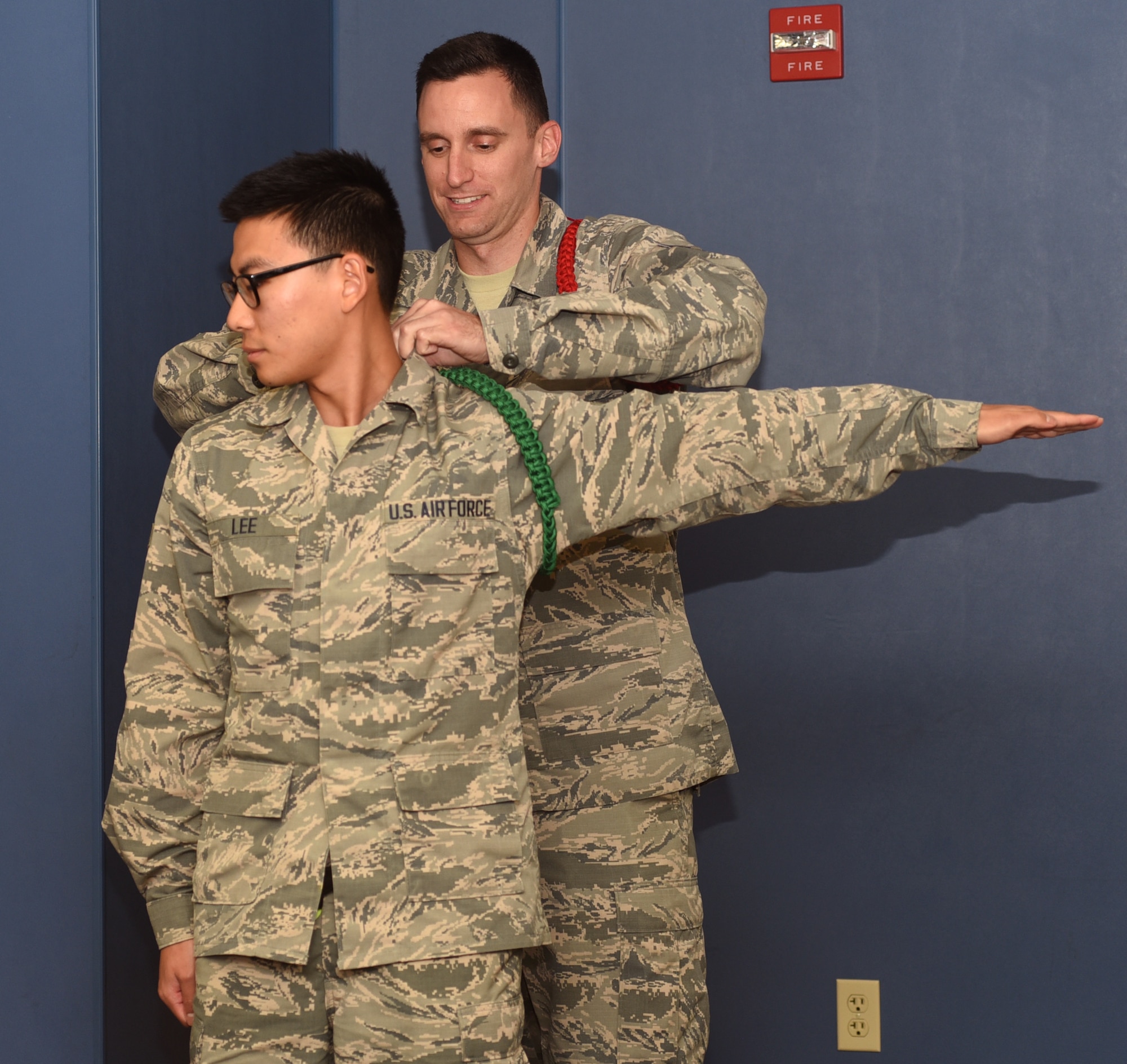 U.S. Air Force Airman 1st Class Spencer Neveaux, 316 Training Squadron student and red rope level Airman Leader, pins a green rope onto Airman 1st Class James Lee, 316th TRS student at the 316th TRS  on Goodfellow Air Force Base, Texas, May 14, 2019. Lee was one of five Airmen selected for the entry level Airman Leader position after completing six weeks of the on the job training while fulfilling a variety of Whole Airman tasks. (U.S. Air Force photo by Airman 1st Class Abbey Rieves/Released)