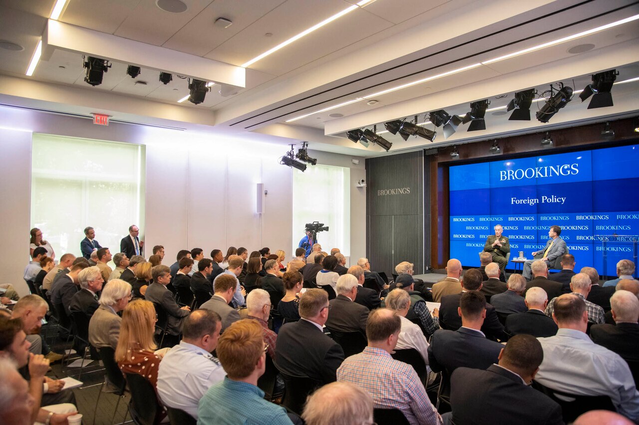 Audience in foreground as Joint Chiefs chairman participates in moderated discussion.