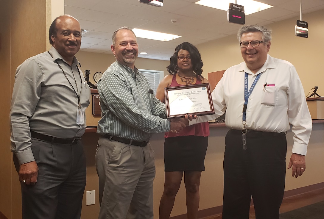 Three members of the Pass and ID RAPIDS team and the Security and Emergency Services division chief stand for photo with the Rapids High Flyer award certificate.