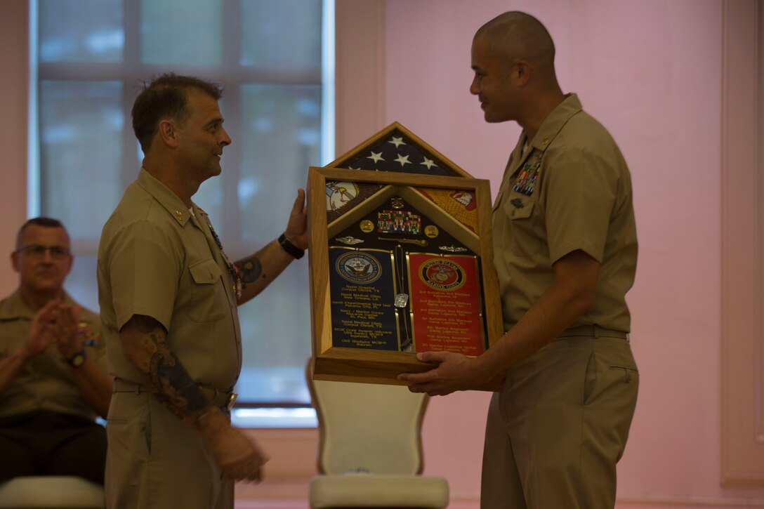 Command Master Chief Petty Officer Russell Folley is presented a gift during his retirement ceremony on Camp Lejeune, N.C., May 24, 2019. Folley, a St. Martinville, Louisiana native, is retiring after 33 years of service in the U.S. Navy. Folley described one of the favorite things in his career was watching both Marines and junior Sailors succeed. He added at the end of his speech during the ceremony that his best moments in the Navy were while wearing Marine pattern utilities. (U.S. Marine photo by Cpl. Leynard Plazo)