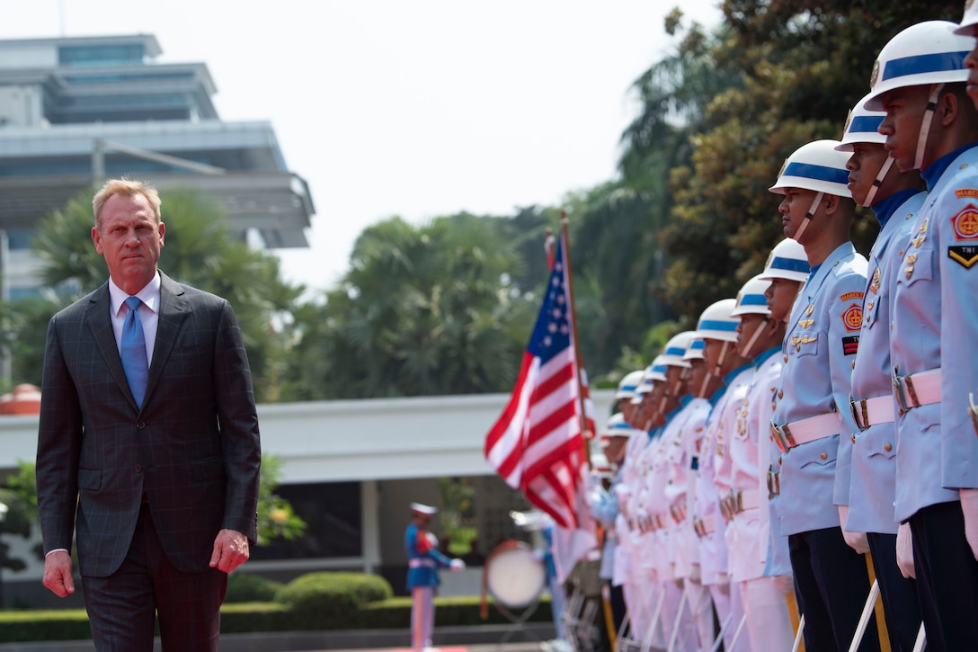 Acting Defense Secretary Patrick M. Shanahan walks in front of a line of troops.