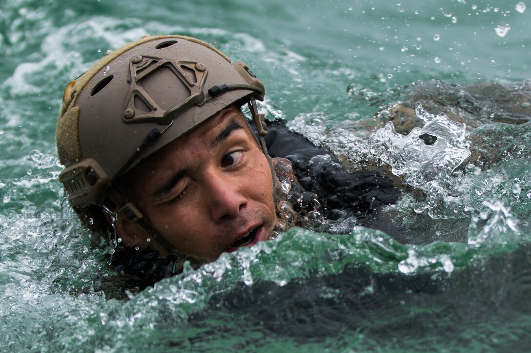 A Marine swims through the water with one eye open.